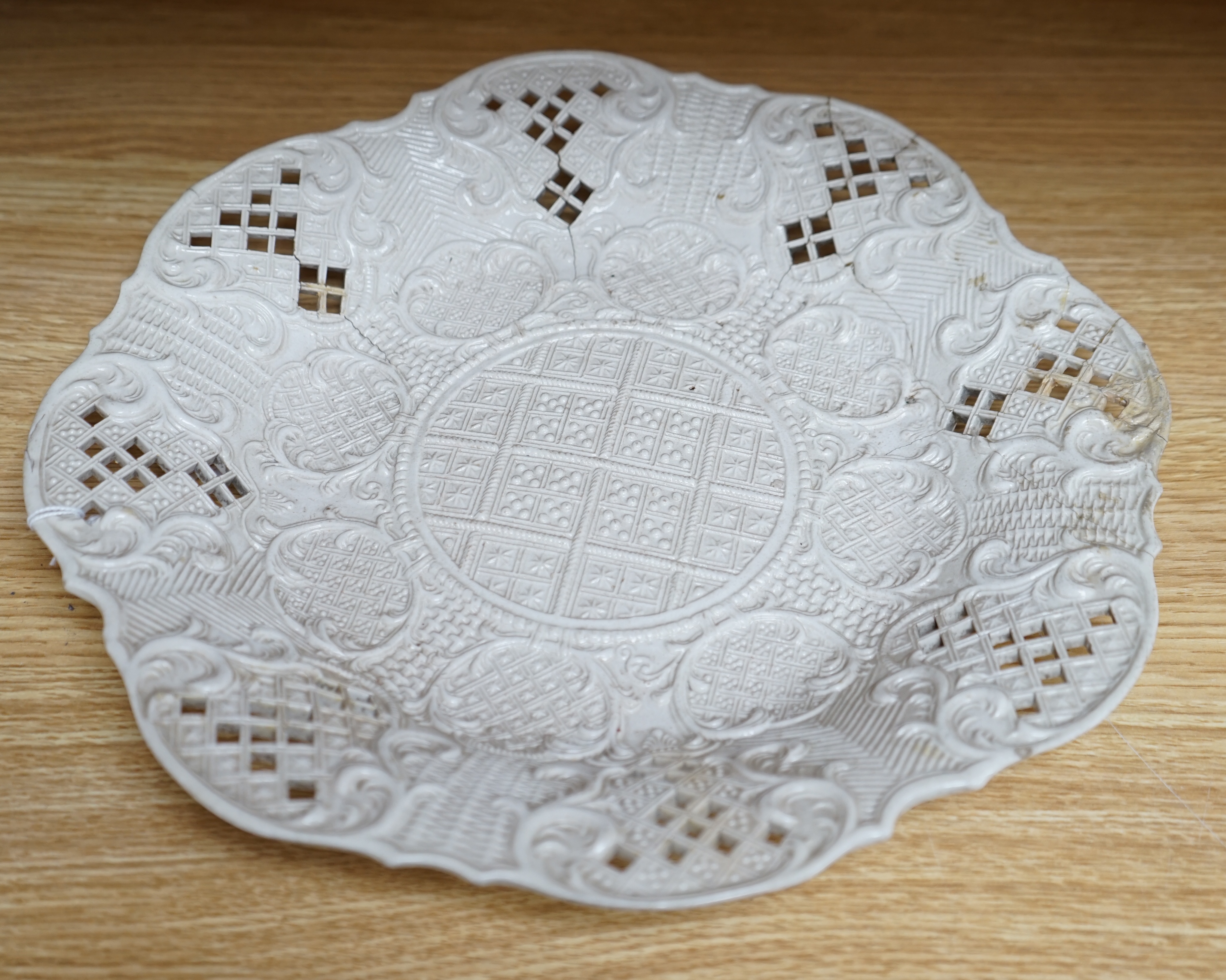 An 18th century white salt-glaze dish, diameter 31cm. (a.f.). Condition - poor, significant cracks and repair